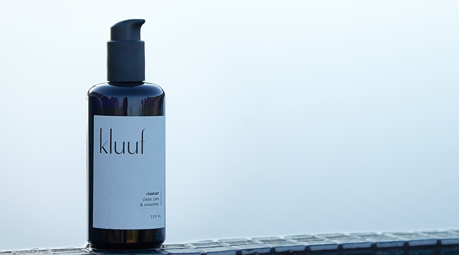 Kluuf's gentle facial cleanser for men positioned on the edge of a pool, overlooking the water
