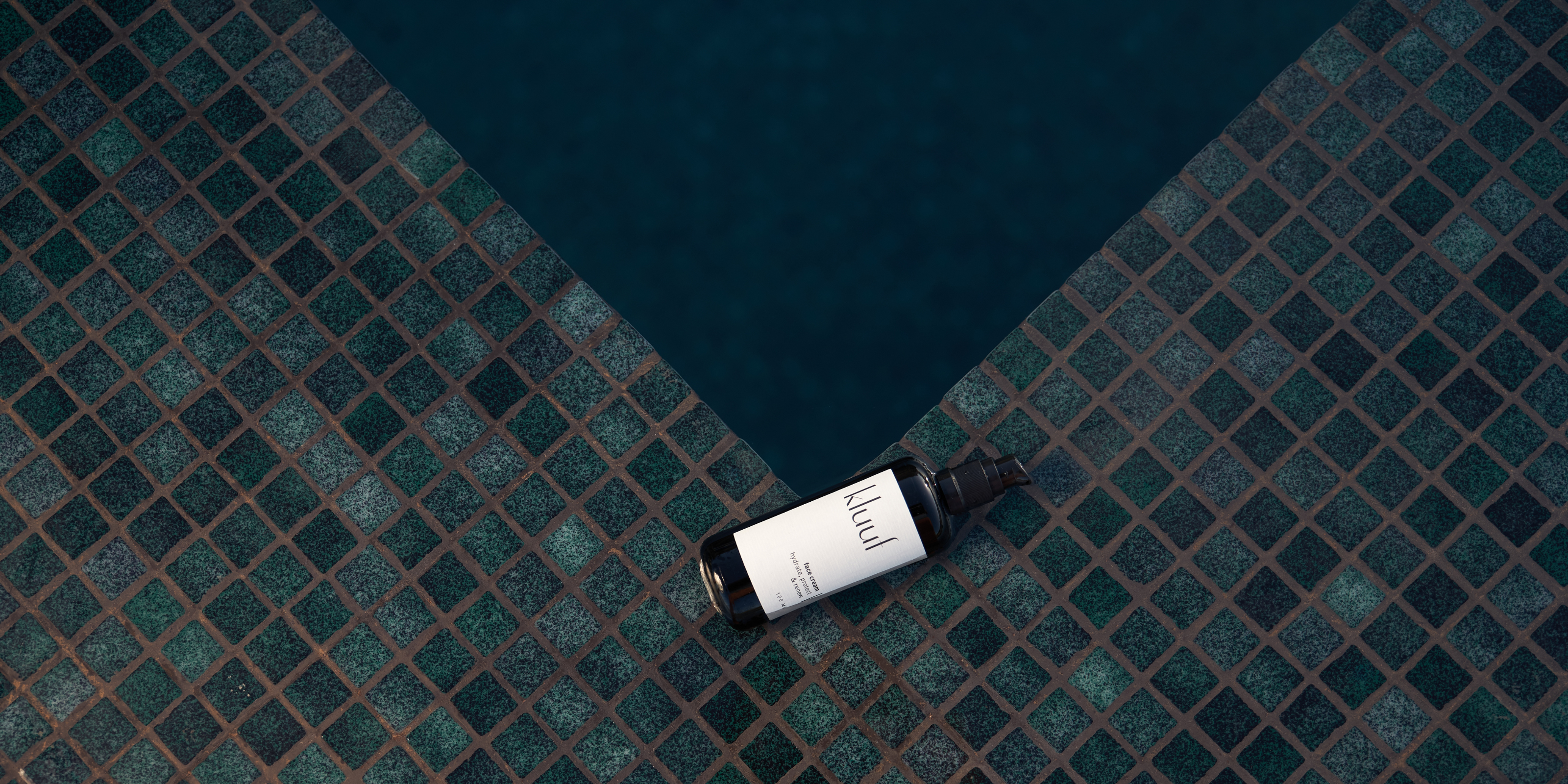 kluuf face cream auf blauen Steinmosaik neben Wasser