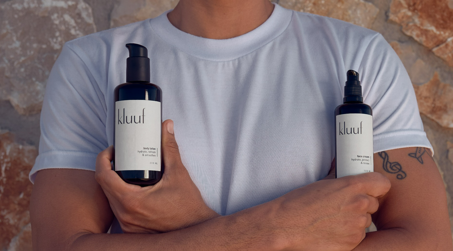 Kluuf's body lotion and face cream held in front of male upper body